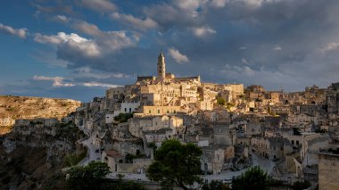 The ancient city of Matera reveals its unique architecture, with charming stone houses and a stunning skyline set against an extraordinary sunset and moody clouds. A perfect moment of tranquility. clipart