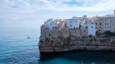 Polignano a Mare Italy 'nin pitoresk bir köyünde, Adriyatik Denizi' nin çarpıcı mavi sularına tepeden bakan, dramatik uçurumların tepesine tünemiş, bembeyaz binalar yer alıyor..