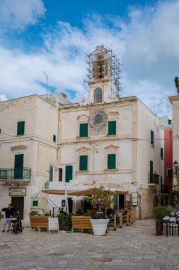 Polignano a Mare Italy, 18 Eylül 2024, İtalya 'nın Puglia şehrinin keyifli sokaklarında gezinirken, tarihi mimarinin canlı kafelerle buluştuğu yerde, aydınlık bir günde büyüleyici bir atmosfer yarattı..