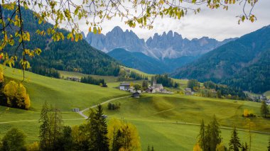 Dolomitlerin kalbinde, sonbahar renkleriyle süslenmiş yuvarlanan tepeler güzel bir zemin oluşturur. Büyüleyici köyler manzarayı süslüyor, Santa Maddalena Val di Funes İtalya