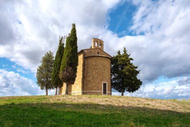 Yuvarlanan tepelerin arasında, bu büyüleyici şapel gururla duruyor, gür ağaçlar ve canlı gökyüzü tarafından çerçevelenmiş, Tuscany 'nin büyüleyici kırsalını huzurlu bir şekilde gösteriyor..
