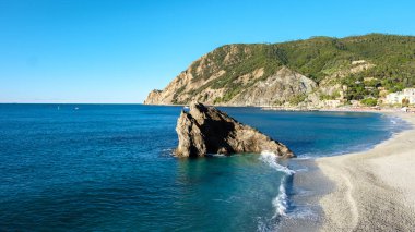 Cinque Terre 'de sakin bir günde canlı mavi sularda ve yumuşak kumlu plajlarda sakin, berrak bir gökyüzünün altında hafif dalgalar görülür. Monterosso İtalya