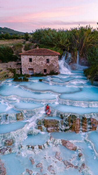 Visitors soak in the warm, mineral-rich waters of the Saturnia thermal baths, surrounded by stunning landscapes and cascading waterfalls, creating a perfect blend of relaxation and nature.