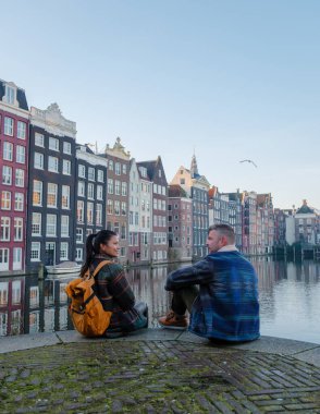 İki arkadaş, Amsterdam 'daki tarihi binaların büyüleyici sonbahar renklerine hayran kalarak huzurlu kanalda oturuyorlar. Sıcak atmosfer, bu pitoresk mevsimde keşif ve bağlantı yapmaya davet ediyor..