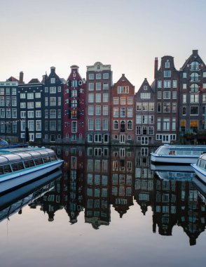Güneş Amsterdam 'ın üzerinde batarken, bu tuhaf kanal büyüleyici tarihi binaların canlı renklerini yansıtıyor. Gemiler, şehrin sakin sonbahar atmosferini yükselterek yavaşça suda dinleniyor..