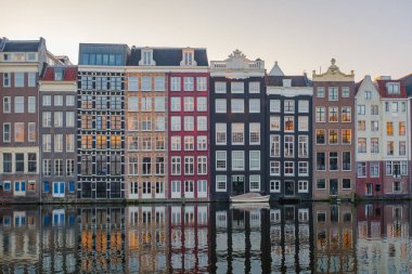 Amsterdam 'ın kanallarını çevreleyen ikonik, dar binaların üzerinde altın yapraklar dalgalanıyor ve güzel bir sonbahar manzarası yaratıyor. Sakin sular, alacakaranlıktaki güzelliklerini yansıtır..