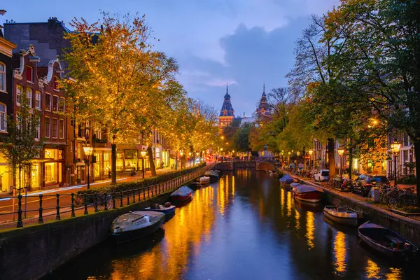Alacakaranlıkta Amsterdam 'ın sakin kanallarını çerçeveleten altın yapraklar, Amsterdam Hollanda' nın Noel ışıkları ile dolu kanalları, Amsterdam 'ın gece kanal tarihi merkezi