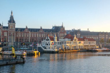 Amsterdam 23 Ekim 2024 'te, Amsterdam Merkez İstasyonu' nda sonbahar renkleriyle süslenmiş tarihi binaların sergilendiği Amsterdam kanallarının sakin sularından altın güneş ışığı yansıyor.
