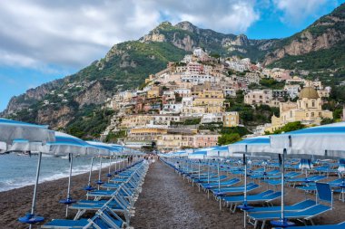 Positano 'nun kumlu plajı boyunca güneş pansiyonları, çarpıcı yamaç köyüne doğru bir yol açıyor. İtalya 'da Positano Amalfi Sahili