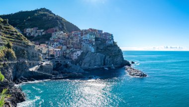 Manarola açık mavi gökyüzünün altında parıldıyor, derin denizin üzerindeki kayalık kayalıklara tutunan renkli evleri. Manarola Cinque Terre İtalya 'da