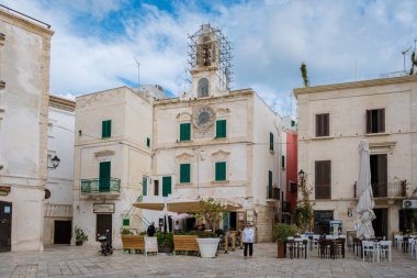 Polignano a Mare Italy 18 September 2024, Serene atmosphere of a quaint Puglia square featuring historic buildings, inviting outdoor seating, and friendly locals enjoying leisurely moments clipart