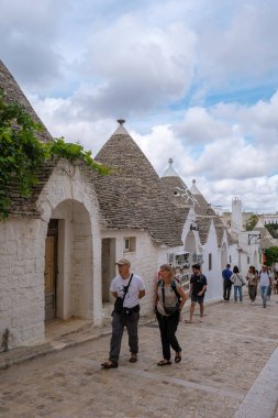 Alberobello İtalya 18 Eylül 2024 Ziyaretçiler Alberobello 'nun dar sokaklarında, konik çatıları olan ikonik trulli binalarla çevrili geziyorlar..
