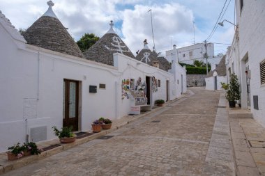 Alberobello İtalya 18 Eylül 2024 Dar, dolambaçlı bir cadde boyunca izole edilmiş renkli trulli ziyaretçileri Puglia 'nın eşsiz mimarisini keşfetmeye davet ediyor..