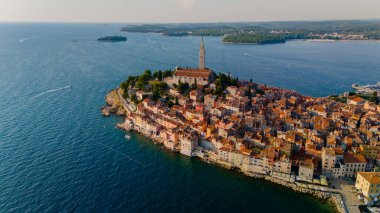 Antik Rovinj kasabasına bakan gök mavisi dalgaları, yüksek kilise tarafından taçlandırılan renkli binalara nazikçe sarılıyor. Bu resim gibi manzara, altın saatinde sahil yaşamının cazibesini yakalar..