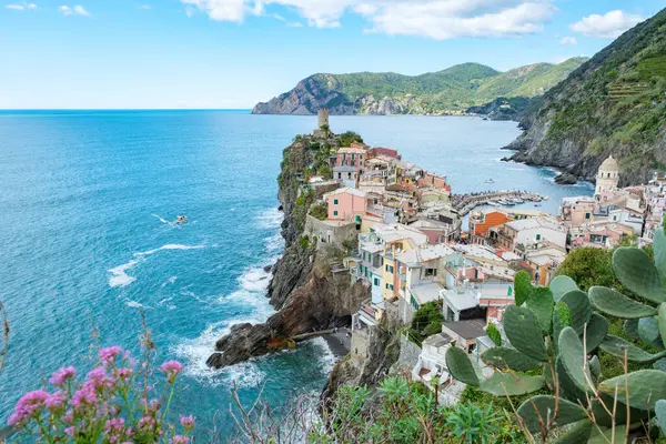 İtalya 'nın kayalık kayalıkları boyunca renkli evler tünemiş dalgalar kıyıya hafifçe vururken. Cinque Terre 'nin nefes kesici manzarası İtalya' nın Liguria bölgesindeki güzelliği gözler önüne seriyor..