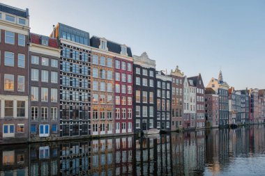 Sonbahar Amsterdam 'ı altın ve turuncu gölgelerle kaplarken şehrin ikonik kanal evleri sakin sularda parlıyor. Damrak Amsterdam