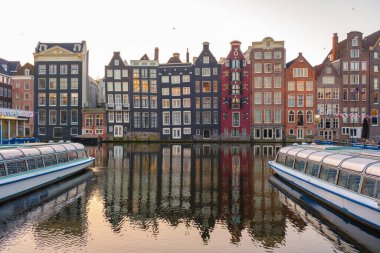 Güneş Amsterdam 'ın üzerinde batarken, canlı sonbahar renkleri tarihi kanal evlerini kuşatıyor, yansımaları durgun suda parıldıyor..