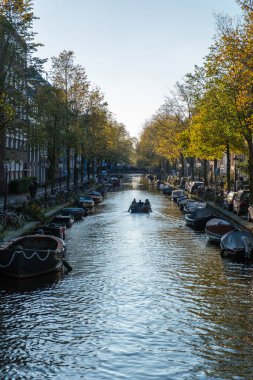 Sonbahar manzarayı resmederken, Amsterdam kanalları üzerinde sükunet hüküm sürüyor, ağaçlar altın yapraklarla parıldıyor ve kayıklar nazikçe yansıtıcı sularda süzülüyor, nefes kesici bir manzara yaratıyor..