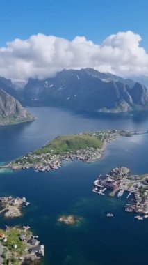 Norveç kıyı şeridinin nefes kesici güzelliğine tanık olun. Resimli adaların berrak bir yaz gökyüzü altında sakin sularla buluştuğu yer. Reinebringen, Reine, Lofoten, Norveç