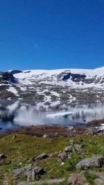 Buzul oluşumlarının sakin sularla buluştuğu, parlak mavi gökyüzünün altındaki karlı dağları yansıttığı Norveç 'teki çarpıcı arazide yolculuk. Doğanın sakinliğini hisset..