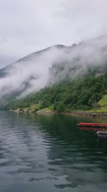 Norveç 'in sakin ve çarpıcı manzarasını deneyin. Bulutlar dağları nazikçe kucaklıyor ve sakin sular ihtişamı yansıtıyor. Geiranger vahşi içine mükemmel bir kaçış
