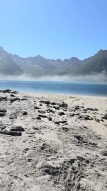 Norveç 'in kumlu kıyılarında sakin bir an yaşayın. Nazik dalgaların, berrak mavi gökyüzünün altında nefes kesen dağlarla buluştuğu ve doğada mükemmel bir kaçış sağlayan güzellik..