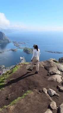 Bir insan, Lofoten kıyı şeridinde kayalık arazi ve sakin bir okyanusla çevrili muhteşem bir manzaranın keyfini çıkarıyor.. 