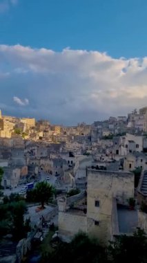 Matera İtalya 'nın büyüleyici manzarasının üzerinde güneş batarken antik mağara evleri altın renklerde parlıyor. Tarihte gezinirken, biri bu büyüleyici bölgenin sırlarını keşfeder..