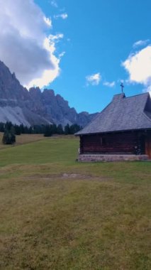 Dolomitlerin kalbinde, parlak mavi gökyüzünün altındaki geniş bir çayırda büyüleyici bir kulübe bulunur. Arka planda yükselen zirveler huzurlu bir kaçış yaratıyor..