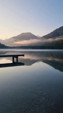 Sisin durgun sulardan yavaşça yükseldiği sakin bir sabah, dağları yansıtıyor ve derin düşüncelere ve rahatlamaya davet eden barışçıl bir atmosfer yaratıyor. Plansee Avusturya 'da