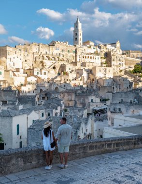 Bir çift el ele durur, Matera İtalya 'nın nefes kesici manzarasına hayran kalarak güzel bir gökyüzünün altındaki antik taş binalar. Puglia tarihinin cazibesi gün batımında büyülenir..
