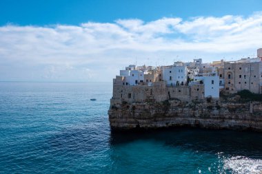 Polignano a Mare Waves nazikçe Puglia 'nın engebeli kayalıklarına çarpar ve İtalya' nın sakin Akdeniz sularına bakan beyaz renkli binaları gözler önüne serer.