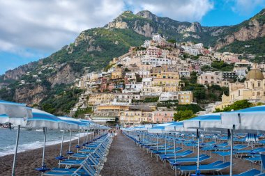 Ziyaretçiler, canlı uçurum kenarındaki evler ve kıyıya vuran nazik dalgalarla çevrili Positano kumsalında huzurlu bir günün tadını çıkarıyorlar. Sahne, İtalya 'nın Amalfi Sahili' nin özünü yakalıyor.