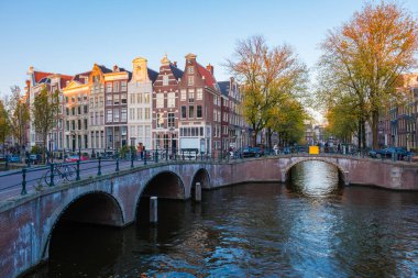 Amsterdam 'da güneş batarken, canlı sonbahar yaprakları Amsterdam Keizersgracht kanalları boyunca çarpıcı bir palet oluşturur.