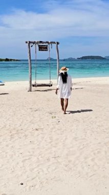 Samae San Adası 'nın el değmemiş sahillerinde bir kadın yürüyor, kıyıda hafif dalgalarla. Güneş bir figür olarak parlıyor Tayland 'ın huzurlu ortamının tadını çıkarıyor. Çeviri: Samae San Adası 