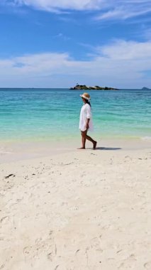 Samae San Adası 'nın yumuşak kumlarında yürüyen Asyalı bir kadın. Sakinleştirici türkuaz sulara ve nazik dalgalara tanık olun. Kıyıyı öperken, Tayland 'da mükemmel bir kaçış yaratıyorlar..