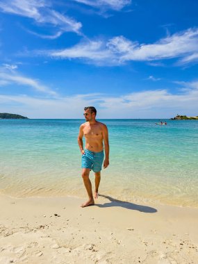 Enjoy the warm sun and soft sands of Samae San Island in Thailand, where gentle waves lap at the shore as a person strolls along the beach, soaking in the serene atmosphere and breathtaking views. clipart