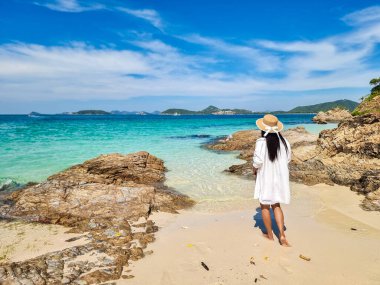 Dalgalar yavaşça kıyıya vurur bir gezgin çıplak ayakla yürür Samae San Island Tayland kumsalında, şapkalı Asyalı kadın Pattaya yakınlarındaki sahilde dinlenir.