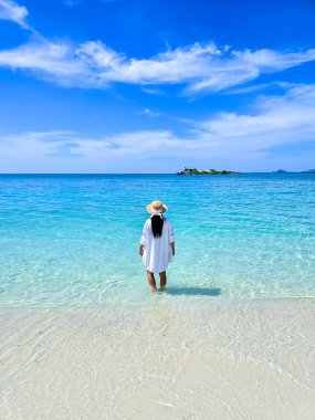 Samae San Adası 'nda sakin bir an. Taylandlı bir kadın, güneşli Tayland' da güneşli bir günde, büyüleyici turkuaz suları ve yumuşak kumlu plajlarla çevrili, yumuşak dalgalarda duruyor.