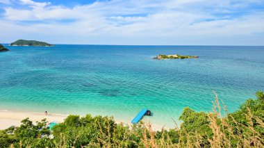 Kristal berrak sular, yemyeşil çimlerin Tayland 'ın sakin manzarasını çerçevelediği Samae San Adası' nın kumlu sahillerini kucaklıyor.