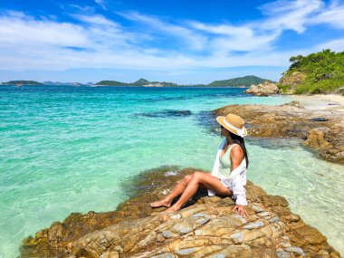 Güneşle öpülmüş plajlar ve turkuaz sular Samae San Island Tayland 'da sakin bir kaçış sağlar. Bir kadın ziyaretçi kayalıklarda dinleniyor, sıcak, sakin atmosferin ve çarpıcı manzaranın tadını çıkarıyor..