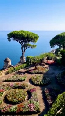 Büyüleyici bahçe, bereketli yeşillik tarafından çerçevelenmiş karmaşık çiçek desenlerini ortaya çıkarırken, aynı zamanda sakin mavi bir deniz manzarası sunuyor. Ravello Amalfi Sahili İtalya