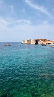 Hırvatistan 'ın Dubrovnik kıyı kasabasındaki antik taş duvarlara çarpan kristal berrak suların nefes kesici güzelliğini deneyimleyin