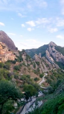 Sarp yamaçlara tünemiş çarpıcı bir köy engebeli dağlara karşı antik mimari eserleri sergiliyor. Güneş batarken manzara sıcacık parlıyor Castelmezzano İtalya