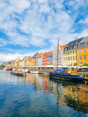 Kopenhag 12 Temmuz 2024, Kopenhag 'da canlı binalar kanalı çevreledikçe güneşli gökyüzü de sudan yansıyor. İnsanlar güzel bir günün canlı atmosferine dalmak için teknelerde vakit geçirmekten hoşlanırlar.