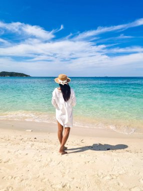 Canlı mavi sular Samae San Adası 'nda gözün alabildiğince uzanıyor. Bir kadın kumlu sahilde sessizce duruyor. Huzurlu atmosferde ıslanıyor ve nefes kesici manzaralar seyrediyor..
