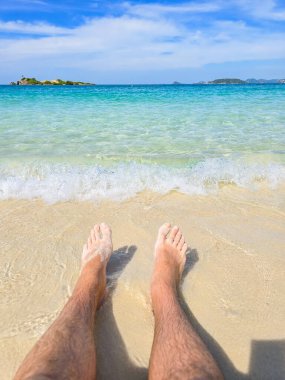 Kristal berrak sular, Samae San Adası 'nın kumlu sahillerinde yavaşça dolaşırken, ılık güneş ışığı huzur dolu sahneyi yıkıyor. Ayaklar hafifçe yumuşak kuma batar, huzuru yakalar..