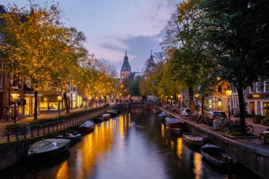 Alacakaranlık Amsterdam 'a çöktüğünde, kanallar altın ışıkların ve sonbahar yapraklarının yansımalarıyla canlanıyor..