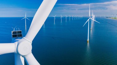 Hollanda 'da mavi gökyüzü yeşil enerji kavramına sahip elektrik üreten yel değirmeni türbinleri, yel değirmeni parkında insansız hava aracı görüntüsü