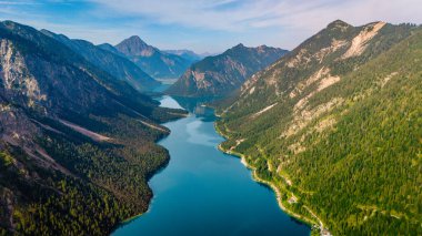 Plansee Avusturya 'nın sakin suları gün batımında sıcak altın saat ile yıkanan çevredeki dağları yansıtır.